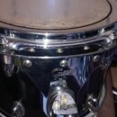 Černý buben s chromovaným obručováním a kováním. Na chromovaném kotevním mechanismu je viditelné logo Gretsch. Povrch blány vykazuje známky opotřeben…