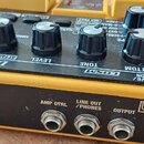Žlutý efekt pedál s černým ovládacím panelem. Na panelu jsou nápisy DRIVE ZONE, LEVEL, TONE, BOTTOM a DRIVE, vpravo je označení OD-20 OVERDRIVE/ OVER…