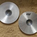 Dva stříbrné kovové činely s viditelným broušením povrchu. Menší činel má černý nápis FRX a pod ním text Hats 14"/35 cm. Oba činely mají v centru čer…