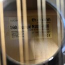 Detail vnitřku těla nástroje s dvěma nalepenými štítky. Na pravém štítku je logo th.omann a nápis MUSIC IS OUR PASSION, dále text Irish Bouzouki M108…