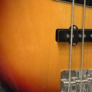 Detail korpusu basové kytary s barevným přechodem od žluté přes oranžovou k červené a černé. Na fotce je vidět černý pickguard, jeden černý snímač a…