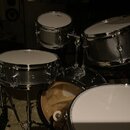 Sada bubnů s nerezovým, stříbrným povrchem a bílými blanami. Na blanách tomů je vidět nápis „Pearl“. Soubor obsahuje tři tomy, malý buben a velký bas…