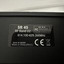 Fotografie detailně zachycuje černý štítek s bílým textem na černém povrchu zařízení. Na štítku jsou nápisy SR 45, RF Band U2 a frekvenční rozsah 614…