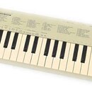 Bílá klávesová klaviatura s plastovým šasi. V pravém horním rohu je černý nápis YAMAHA a pod ním menší, nečitelný text. Horní panel obsahuje několik…