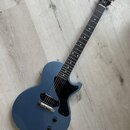 Modře lakovaná elektrická kytara s černým hmatníkem a černým pickguardem. Na hlavě je bílý nápis Gibson a pod ním nápis Les Paul. Nástroj má jeden sn…