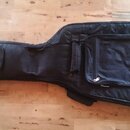 Černý poloměký pouzdro (gig bag) na kytaru s dvěma zipovými kapsami na přední straně. Povrch je z černé textilie s jemnými žlutými lemovými detaily.…