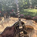 Černá elektrická kytara s tmavým hnedým hmatníkem a bílými vložkami. Na hlavě je bílý nápis Epiphone. Nástroj má dva snímače, stříbrný most a je umís…