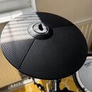Černý elektronický činel z gumového materiálu s koncentrickými drážkami. Na povrchu je v horní části bílý nápis Roland. Činely jsou rozděleny na tři…