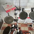 Elektronická bicí souprava s červeným modulem, na kterém je nápis YAMAHA DTXPRESS III. Souprava obsahuje několik černých gumových padů s nápisy YAMAH…