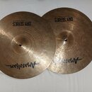 Dvě mosazné činely s viditelným rýhováním povrchu. Na obou je nápis „Anatolian“ a označení „DRY SERIES“. Levý činel nese nápis „15" HI-HAT REGULAR TO…