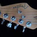 Fotografie zachycuje hlavu dřevěné elektrokytary s pěti chromovanými ladicími mechanismy. Na povrchu je vidět logo Fender, nápis STRATOCASTER a text…