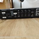 Černý rackový zesilovač s nápisem DEXON JPA 1181 Public Address Amplifier. Přední panel obsahuje řadu regulačních knoflíků, přepínače a USB vstup. Na…