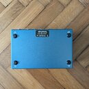 Fotografie zachycuje spodní stranu modrého efekt pedálu z kovu. Na horní části je bílý nápis „strymon.“, pod ním „S/N: S21-71727“ a dále „CE built in…