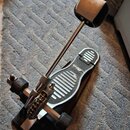 Fotografie zobrazuje bicí pedál s černou základnou a stříbrným kovovým mechanismem. Šlapka je z černého materiálu s bílými protiskluzovými žebrovaným…