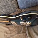 Elektrická kytara s černým lakem a bílým lemováním kolem korpusu. Nástroj má dva humbuckery, dva ovládací knofíky a jeden přepínač. Na korpusu nejsou…