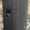 Černý reproduktor v plastovém korpusu s kovovou mřížkou. Na boku je úchop s nápisem kxaudio a v dolní části mřížky se nachází čtvercové logo s písmen…