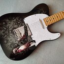 Elektrická kytara s černým bodies, které je zdobeno šedivým ornamentálním vzorem. Nástroj má bílý perleťový pickguard, hmatník ze světlého dřeva a ch…