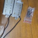 Dva humbuckery s kovovými kryty stříbrné barvy a připojovacími kabely. Na obou jsou nálepicky s označením S/N 082118128 a spodní štítky s nápisy IIZE…