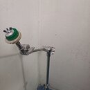 Stříbrný kovový stojan s dvěma klouby a nastavitelnou výškou. Na konci ramene je umístěn zelený kruhový držák s bílým polstrováním. Na stojanu nejsou…