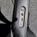 Detailní pohled na černý plastový panel s konektory. Jsou zde vidět čtyři vstupy: kulatý napájecí konektor, malý slot (pravděpodobně SD), jack konekt…
