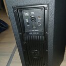 Zadní panel černého aktivního reproduktoru s texturou povrchu. Na ovládacím panelu je logo FAR PHASE, nápis BALANCED INPUT/LINK, přepínač PRESETS a o…