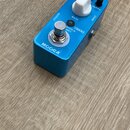 Modrý efekt pedál značky MOOER. Na horní straně jsou tři bílé ovládací knoflíky s popisky LEVEL, RATE a DEPTH. Vedle spínače je nápis Bass Tremble v…