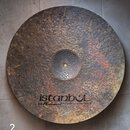 Kulatý činel z kovaného kovu s výrazně hrubým, dympitovaným povrchem a oxidací. Ve spodní části je čitelné logo „istanbul“ a pod ním nápis „Mehmet Ha…