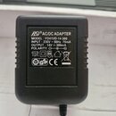 Černý plastový AC/DC adaptér s bílým textem. Na štítku je uveden název FLO® AC/DC ADAPTER, MODEL: FD41VD-14-300, INPUT: 230V ~ 50Hz 70mA, OUTPUT: 14V…