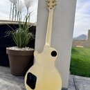 Zadní strana elektrické kytary s králem a tělem v krémové barvě. Na hlavě hnedniku je vidět nápis Gibson a na horní hraně text COBETT. Kytara má zlat…