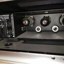 Zadní strana černého elektronického zařízení s několika konektory a ovládacími prvky. Na levé straně je text: MANDELL ENGINEERING, MUNDELEIN, IL., EL…