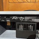 Zadní strana kytarového zesilovače s bílým potahem. Na černém panelu jsou nápisy Peavey ValveKing VK 112, 6L6GC a ALL PREAMP TUBES 12AX7. V pravém do…