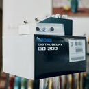Fotografie zobrazuje efekt pedál v originální krabici. Na černé části krabice je bílý nápis DIGITAL DELAY DD-200 a modré logo BOSS. Nad krabicí je um…