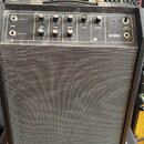 Černý kytarový kombo zesilovač s šedou síťovinou přes reproduktor. Na ovládacím panelu jsou nápisy INPUT, GAIN, BASS, TREBLE, MIDDLE, MASTER a R 222.…