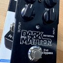 Černý efekt pedál s nápisy DARK MATTER a DISTORTION. Na spodní části je bílé logo tc electronic® a text true bypass. Pedál má čtyři černé ovládací kn…