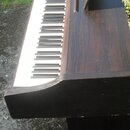 Digitální piano v tmavě hnědé dřevěné provedení s klasickým rozložením bílých a černých kláves. Nástroj je vybaven integrovaným music standem (podpěr…