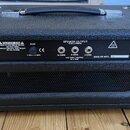 Zadní strana černého kytarového komba s texturovaným povrchem a úchytem. Na zadním panelu jsou nápisy INPUT POWER, FUSE, SPEAKER OUTPUT a logo Z-AMP.…