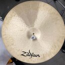Kruhová činely z kovu s hammered povrchem (vkovanými důlky). Na povrchu je černé logo Zildjian. U středu je přilepená bílá štítková nálepka s nečitel…