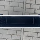 Otevřený transportní kufr s černým vnitřkem a hliníkovými hranami. Uvnitř jsou na obou krátkých stranách umístěny kovové lišty pro montáž rackového v…