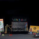 Černý analogový syntetizátor s nápisy moog a MOTHER-32 v dolní části. Přístroj je osazen několika ovládacími knoflíky, přepínači a zapojenými patch k…