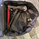 Černý přepravní kufr s vnitřním černým polstrováním, ve kterém je umístěn červený bubnový pedál. Pedál má černou mechaniku a kovový řetěz. Na nástroj…