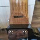 Detail zadní strany hřdelu kytary z lakovaného dřeva a části černého trupu s kovovou chromovanou deskou. Na hřdelu je čitelný nápis MADE IN JAPAN. Po…