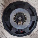 Černý reproduktor s kovovým rámem a vnějšími montážními otvory. Uprostřed je vidět kulatý štít s nápisem PRECISION DEVICES a menším textem Quirton Co…