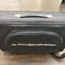 Černý textilní přepravní obal s rukojetí a ramenním popruhem. Na přední kapse je bílý nápis „GK GALLIEN-KRUEGER“. Povrch materiálu vykazuje mírné zne…