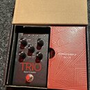 V kartonové krabici se nachází černý efekt pedál s nápisem TRIO Band Creator. Zařízení má několik ovládacích knoflíků, červené tlačítko v dolní části…