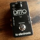 Černý kytarový pedál s nápisy DITTO STEREO LOOPER a tc electronic. Na horní části je přepínač s nápisy LOC a VEL, pod ním texty STORE a BACKING TRACK…