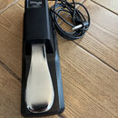 Černý sustain pedál s chromovaným šlapadlem. Na horní části je bílý nápis Stagg a pod ním text SUSPED 10, www.staggmusic.com a Made in China. K pedál…