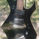 Černá elektrická kytara s ostře hranatým tvarem těla a hnědým hmatníkem. Na hlavě je viditelný nápis HATE a na obou snímačích je logo B.C. Rich. Nást…