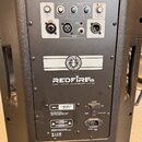 Zadní panel černého aktivního reproduktoru s nápisem REDFIRE15 2-WAY ACTIVE LOUDSPEAKER SYSTEM. V horní části jsou ovládací prvky pro MIC, LINE/AUX a…