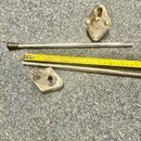 Na šedém koberci jsou položky z kovového materiálu a žlutá skladovací metr značky TOLSEN. Je zde vidět jedna kovová tyč s černou rukojetí, jeden troj…