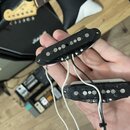 Dva černé elektrické snímače typu humbucker s bílými a černými vodiči. Horní snímač má na krytu nápis "SAYONARA". Povrch obou snímačů vykazuje známky…